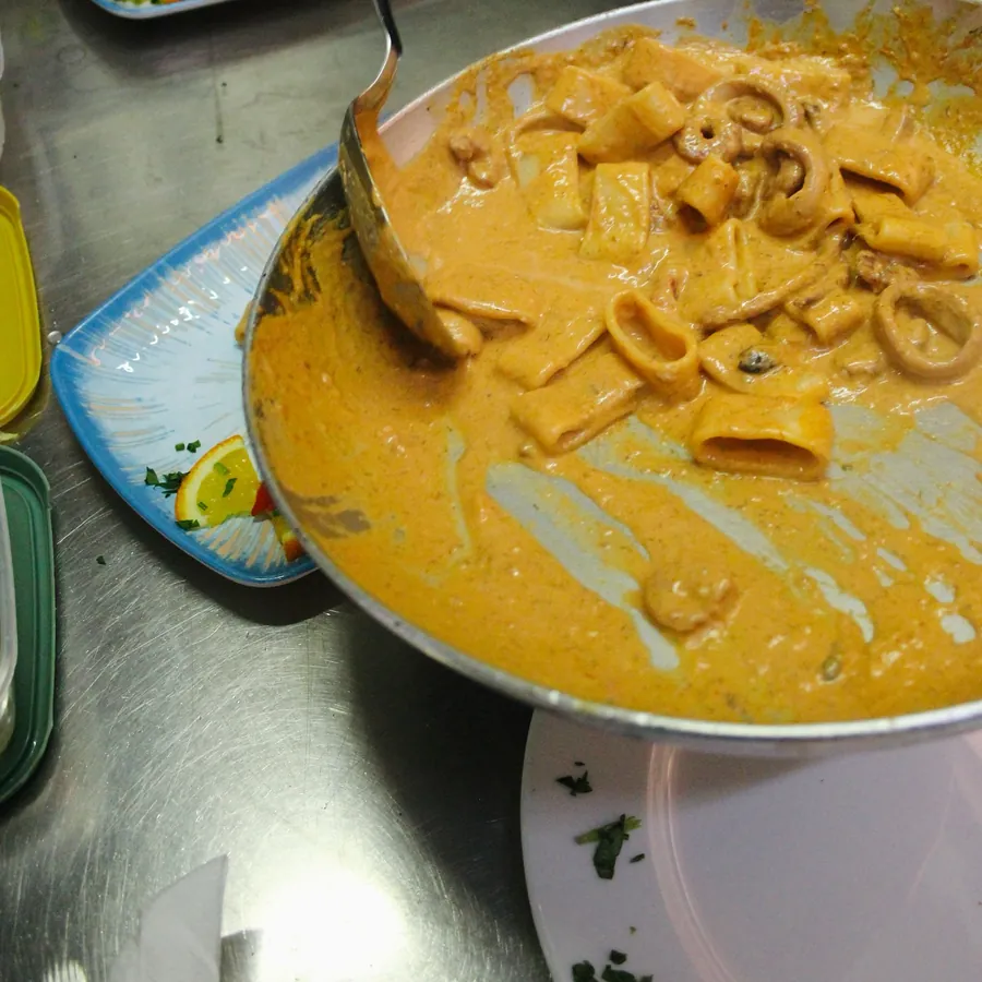La calamarata Rosso Corallo nella padella, con anelli di calamaro e gamberi in un sugo rosato
