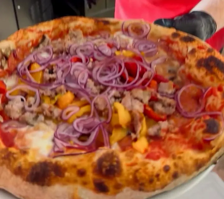 La pizza Messicana appena sfornata, con cipolla rossa, peperoni e salsiccia